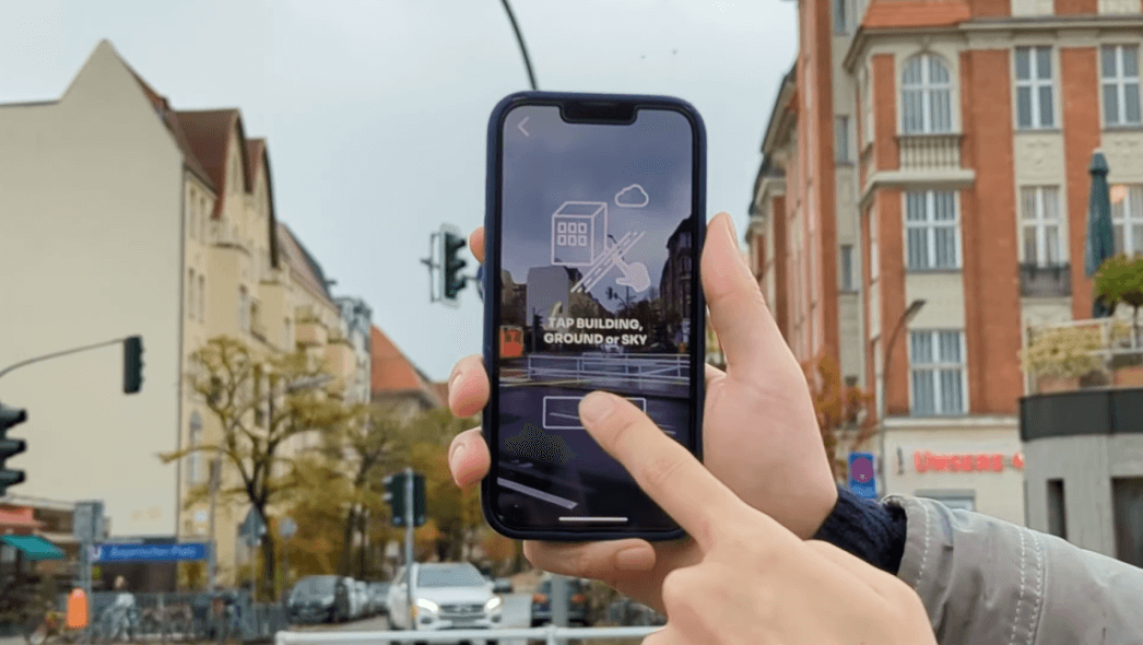 Eine mobile App, die den Nutzer dazu auffordert, auf das Gebäude, den Boden oder den Himmel auf dem Bildschirm zu tippen