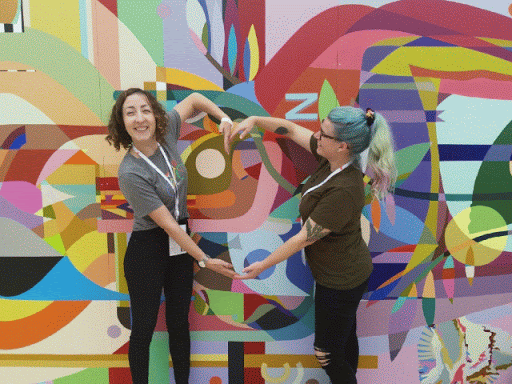 صورة تجمع سيّدتين من المشاركين في مؤتمر Google I/O أثناء تشبيك ذراعَيهما لرسم شكل قلب